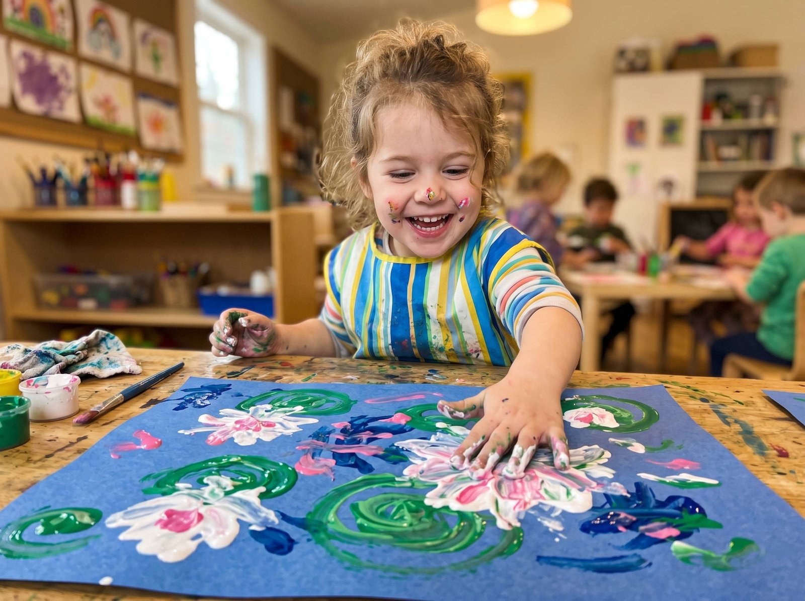 Niño haciendo fingerpainting de nenúfares con dedos sobre papel azul estilo Monet — Los Mundos de Noa