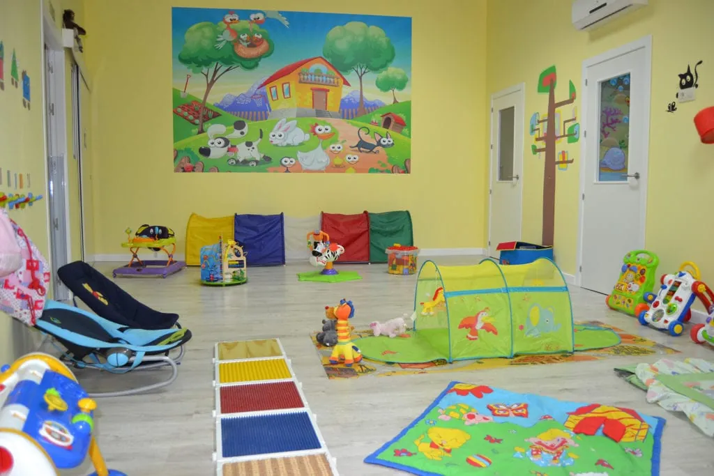 Aula Amarilla con camino sensorial de texturas, túnel de tela y mantas de juego