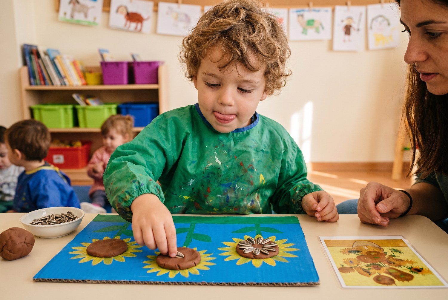 Niño de 3 años colocando pipas con los dedos en pinza sobre el centro de plastilina marrón de su girasol — girasoles de Van Gogh para niños
