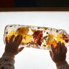 Mesa de luz encendida con la botella sensorial de otoño encima
