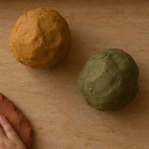 Bolas de plastilina ocre y verde oliva sobre la bandeja de madera